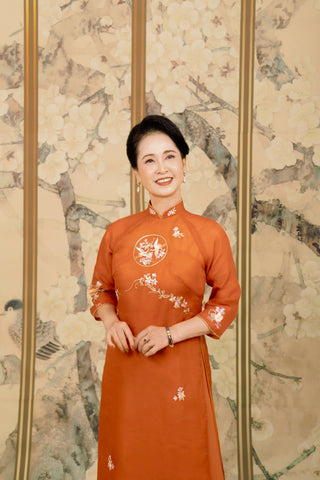 Thiết kế áo dài sui gia Hạc Tranh họa tiết hoa trên nền cam tại La Hằng Design, Hà Nội